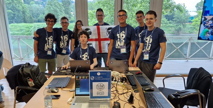 La squadra di giovani studenti che a Torino ha rappresentato UniCa alla finale di CyberChallenge 2023. Al centro con la bandiera Davide Maiorca e Sofia Tocco