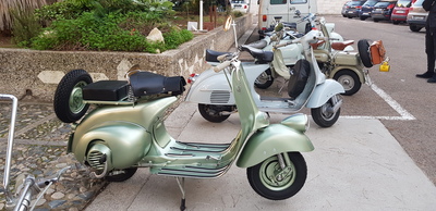 In primo piano uno splendido esemplare di Vespa a faro basso del 1950, con comando a bacchetta del cambio di velocità